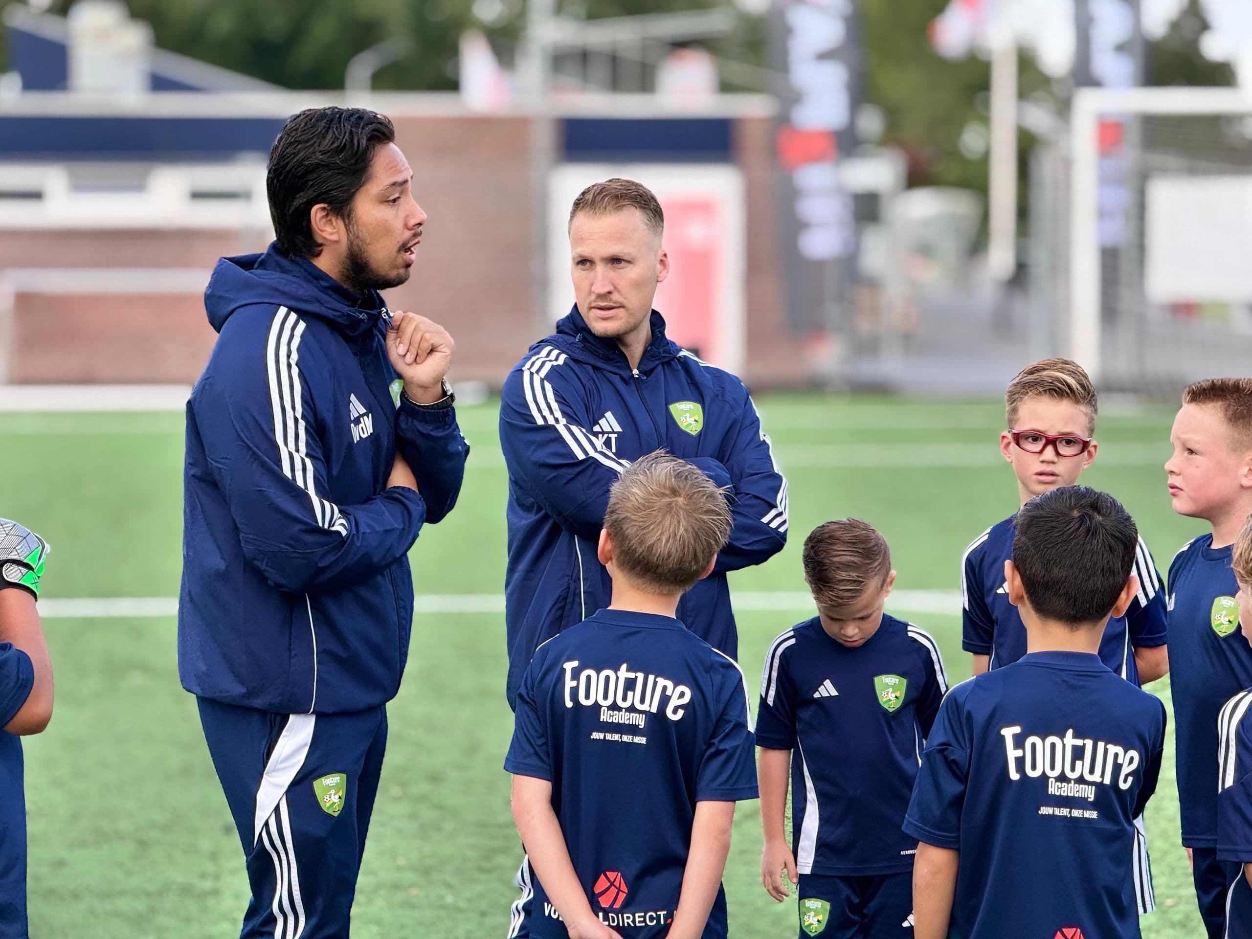 Footure-trainer geeft uitleg aan een groep jeugdspelers.