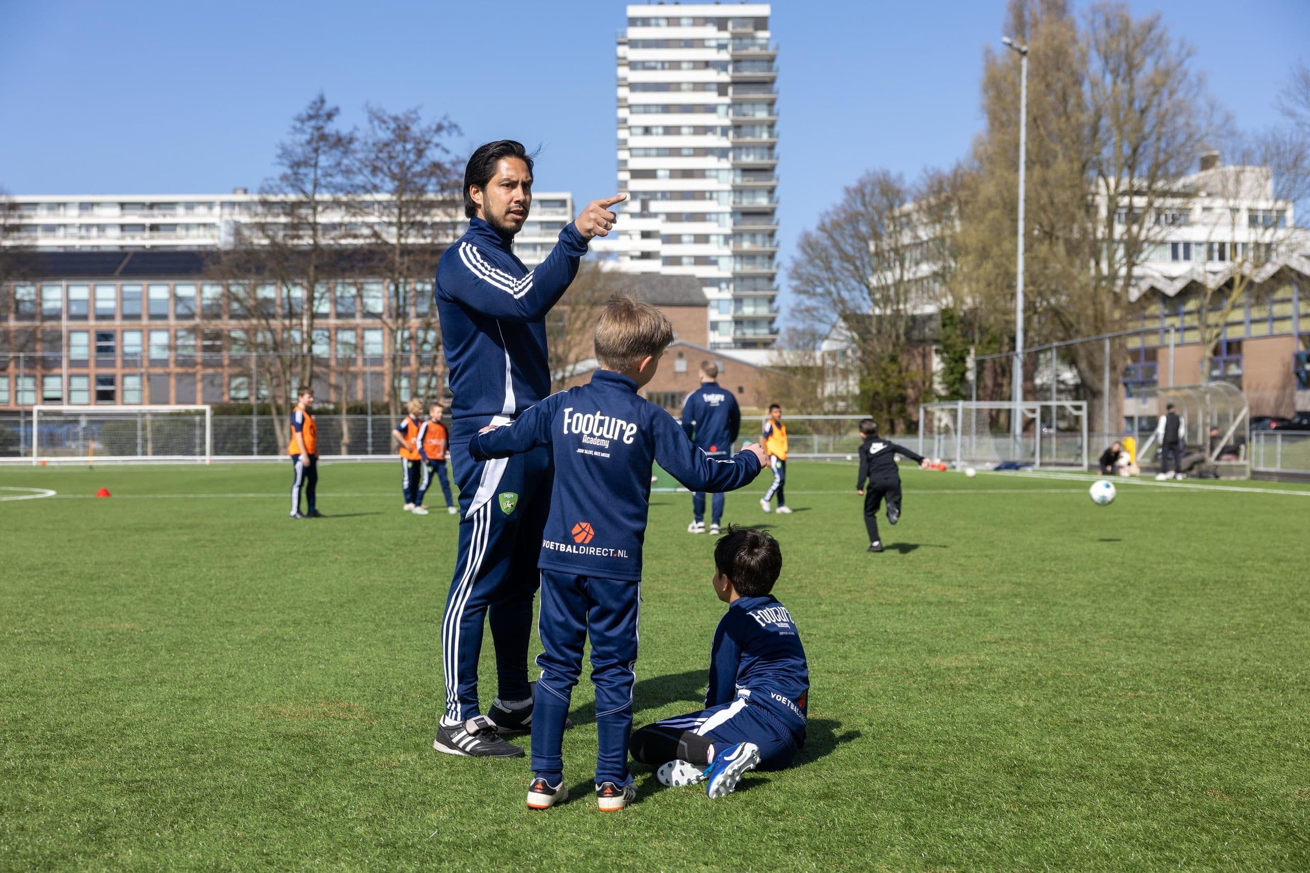 Footure-trainer coacht twee jeugdspelers tijdens een oefenvorm.